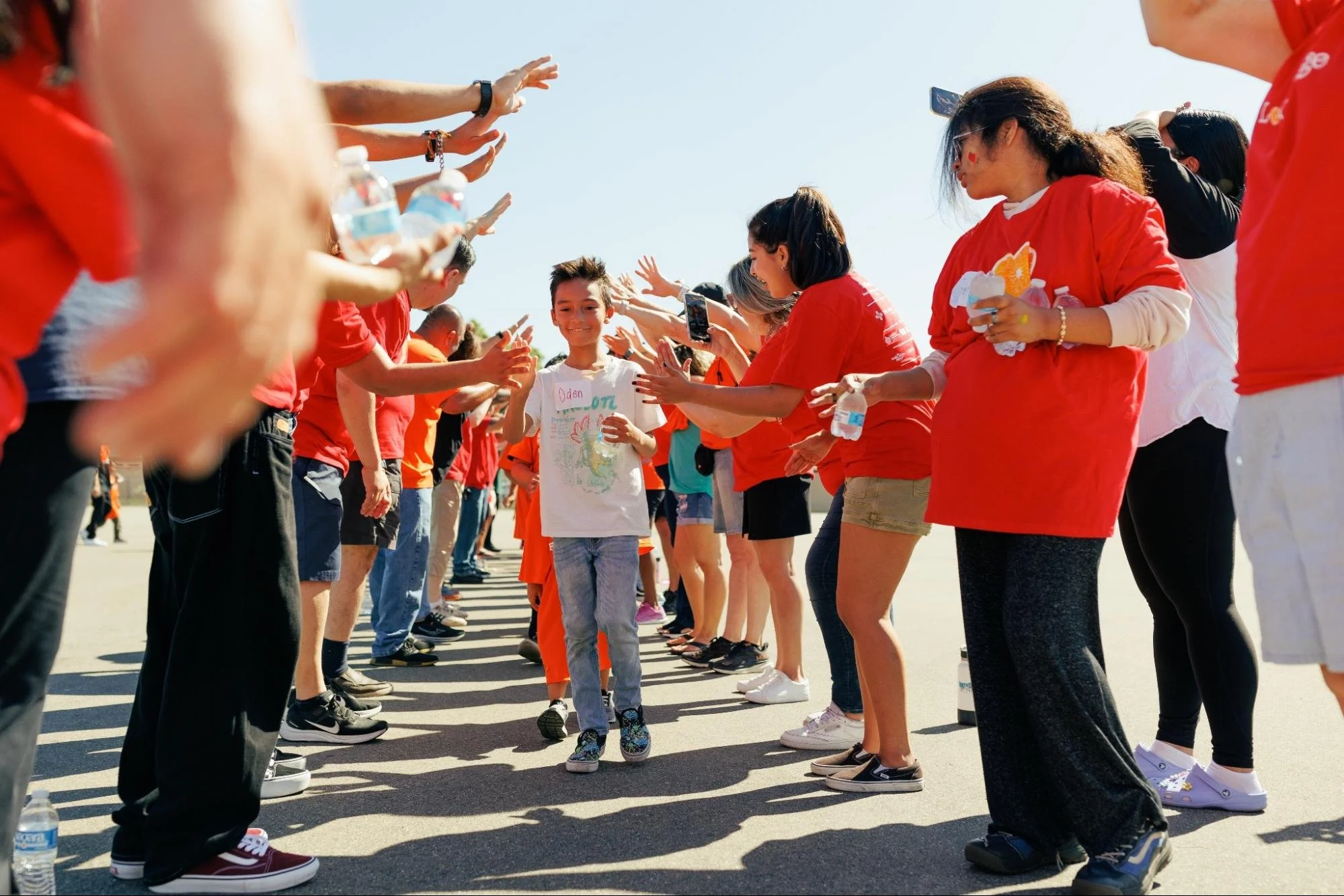    Love Orange event volunteers create a tunnel for the participants of the Fun Run to walk through and feel celebrated.   