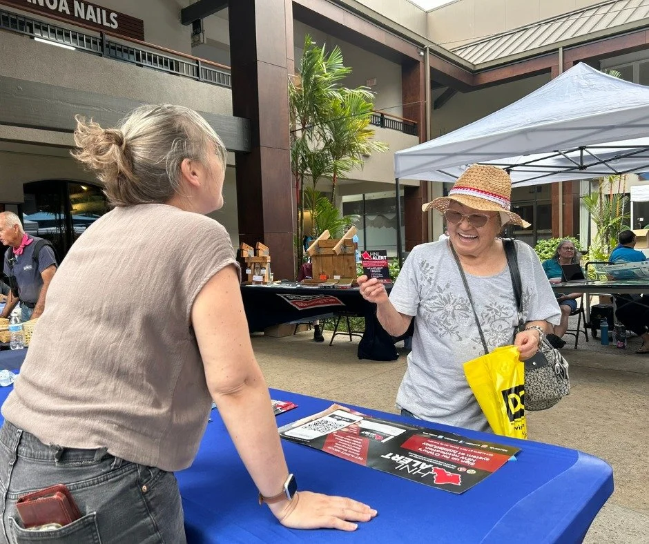 A person smiling learning about HNL Alert from City staff at a tabling event