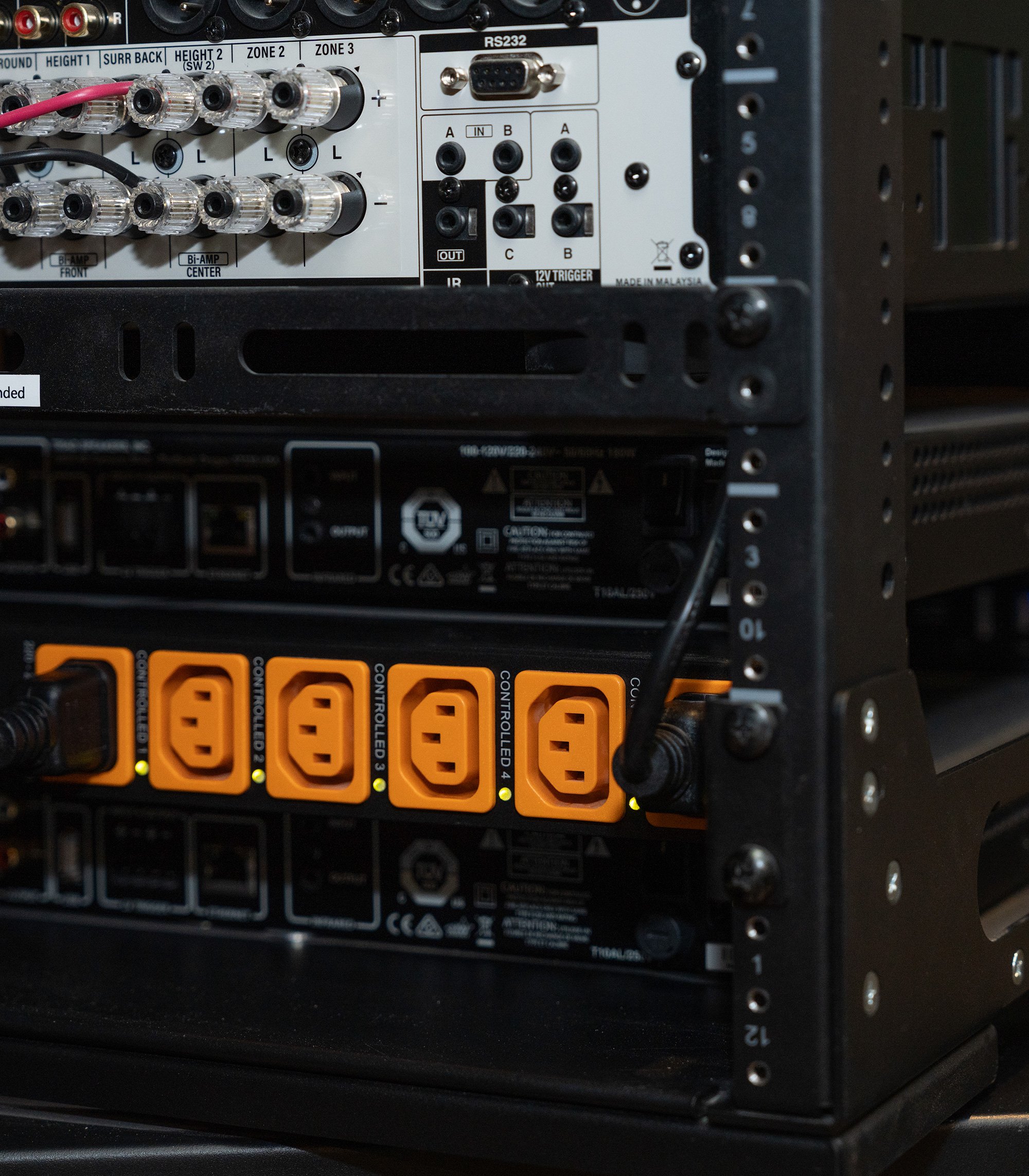 Close-up of a professional smart home equipment rack showing an audio-video receiver and a Wattbox power distribution unit with active orange controlled outlets.
