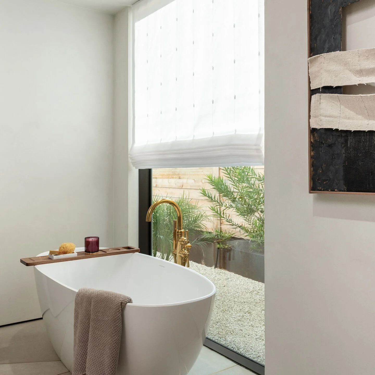 Lutron motorized Roman shade in white sheer fabric providing privacy in luxury bathroom with freestanding tub