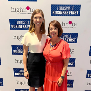 Two women standing in front of a backdrop with Louisville Business First and highNote logos, smiling for the camera at an event.