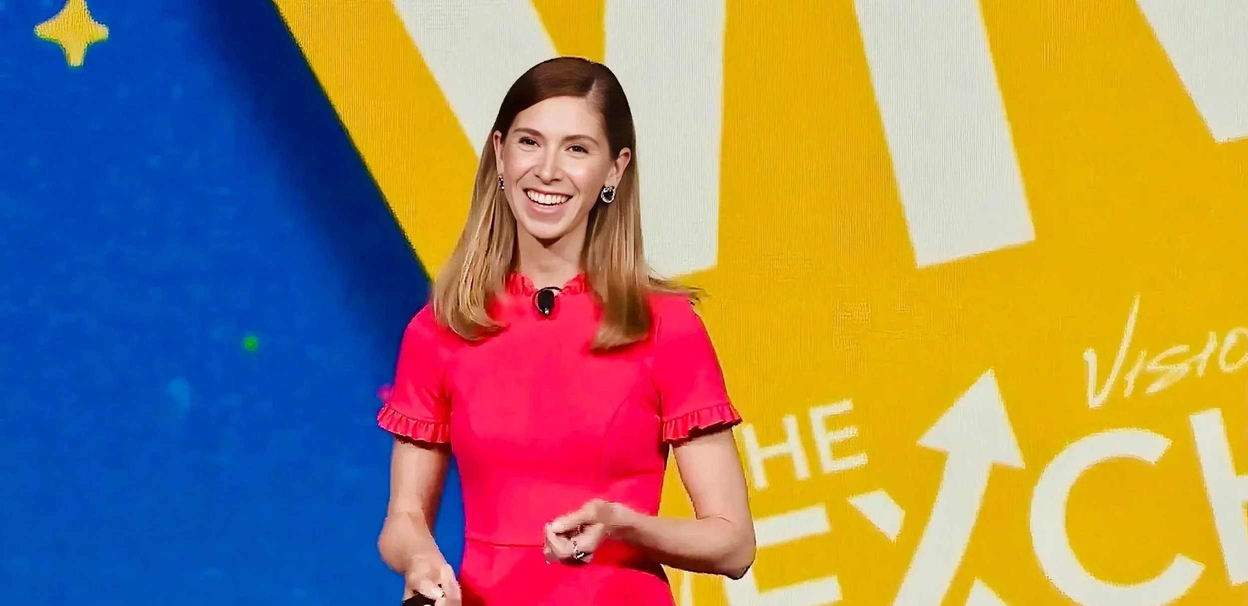 Kristel Bauer smiling with light brown hair wearing a pink dress and earrings standing in front of a colorful background with yellow and white text and graphics.