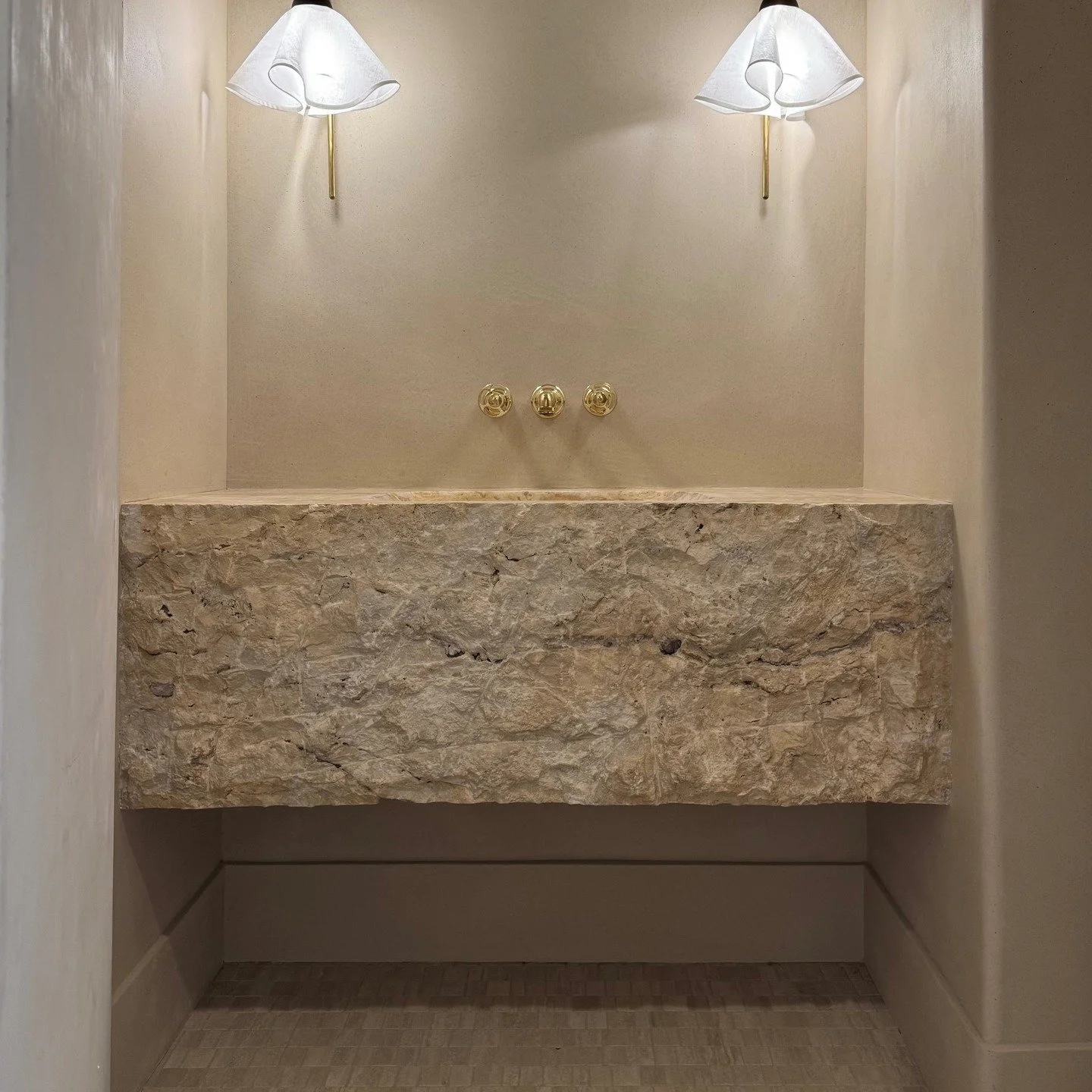 Raw materials meet elegant finishes. 

This powder bath features a massive, rough-hewn limestone vanity/sink, limestone floor tile, and lime plastered walls. Lime plaster is made from limestone and, as it cures, it becomes limestone again on the wall