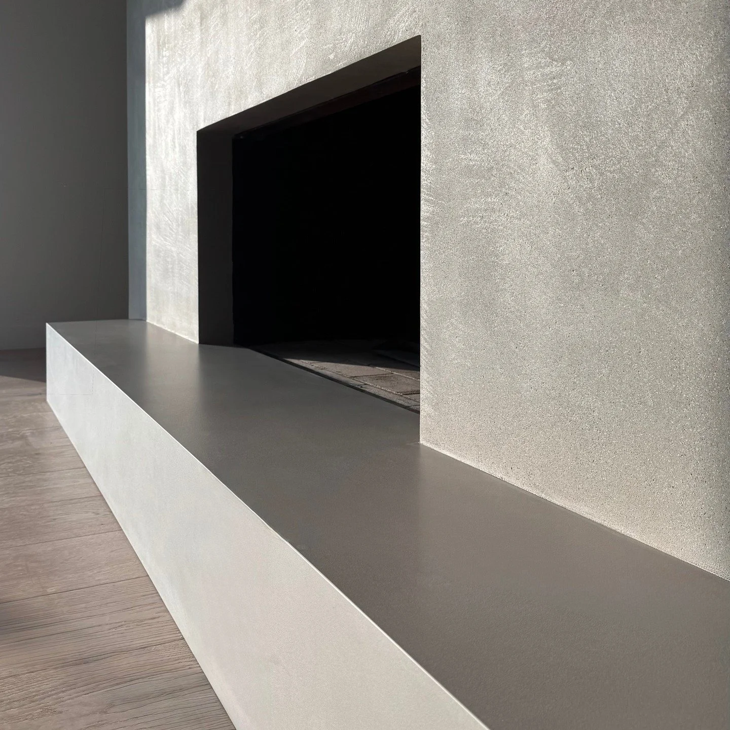 Minimalist fireplace in gray lime plaster with irregularly exposed aggregate. When the shapes and lines are so spare, a little bit of texture does a lot. With its emphasis on simplicity and materiality, this fireplace has a bit of a Brutalist vibe.
#