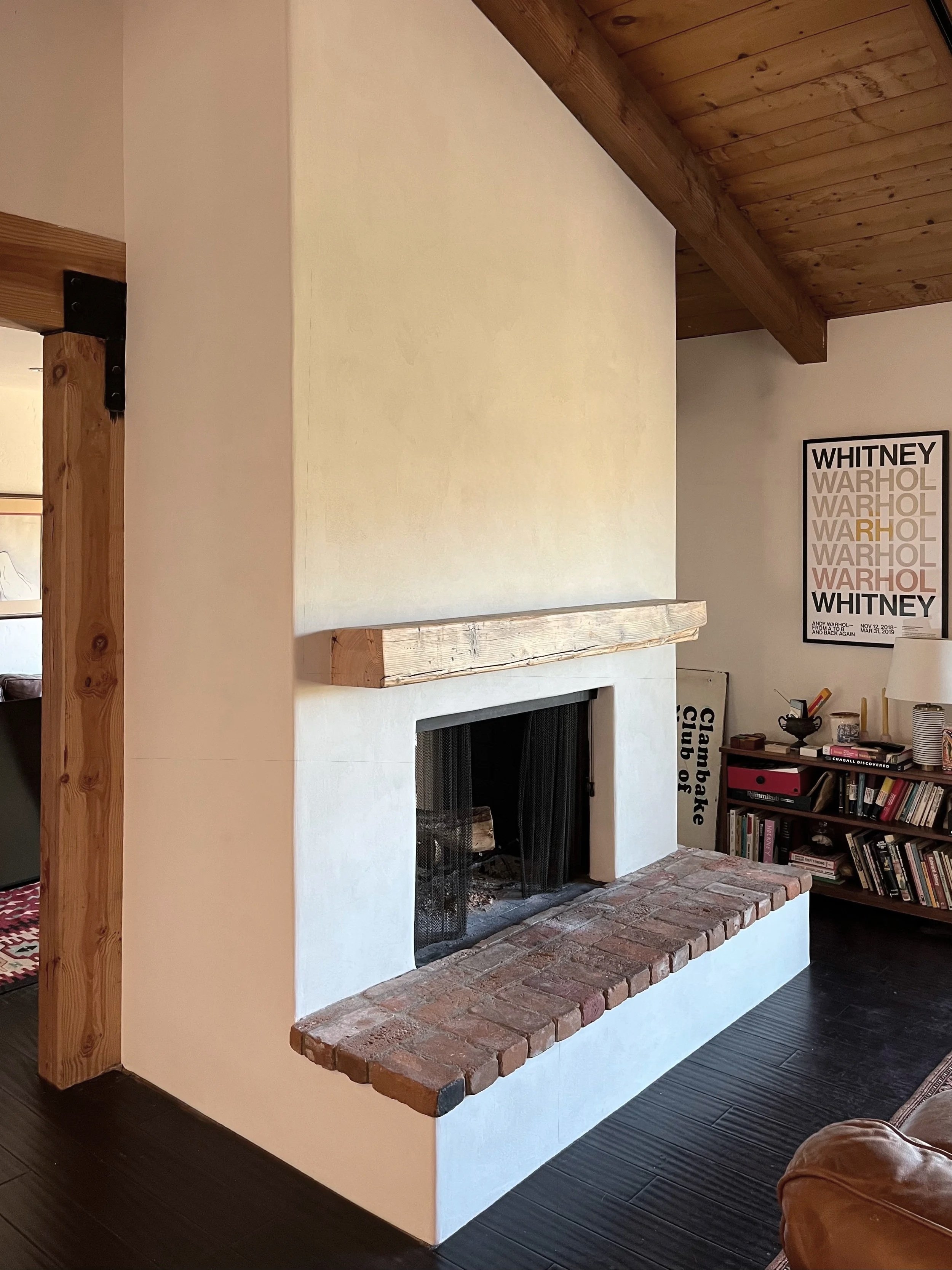 White plastered fireplace with wood mantle and brick hearth