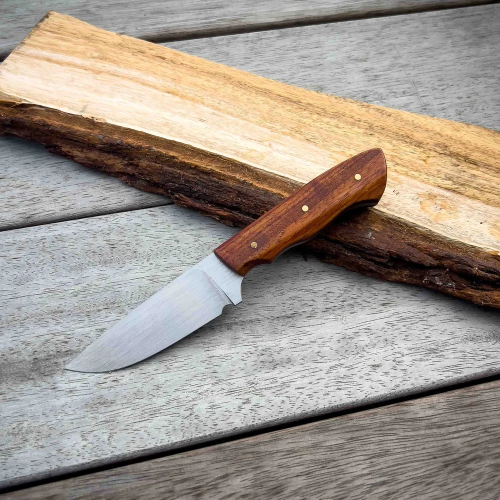 Handmade hunting knife with a timber handle on a slab of wood