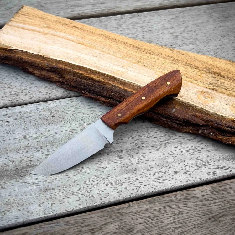 Handmade hunting knife with a timber handle on a slab of wood