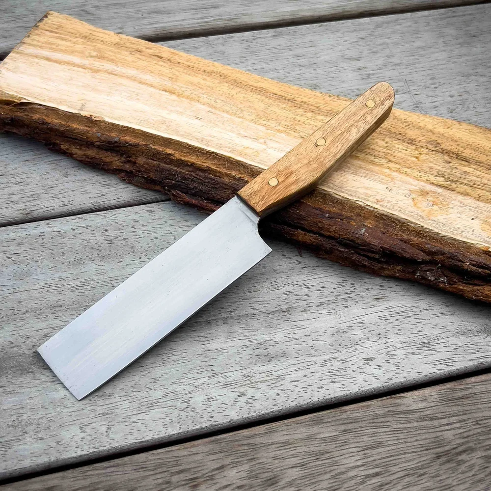 Handmade kitchen knife with a timber handle on a slab of wood