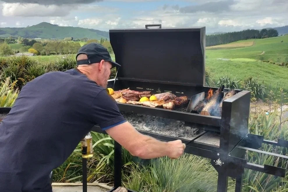 Man cooking meat of a wood-fired Argentinian BBQ