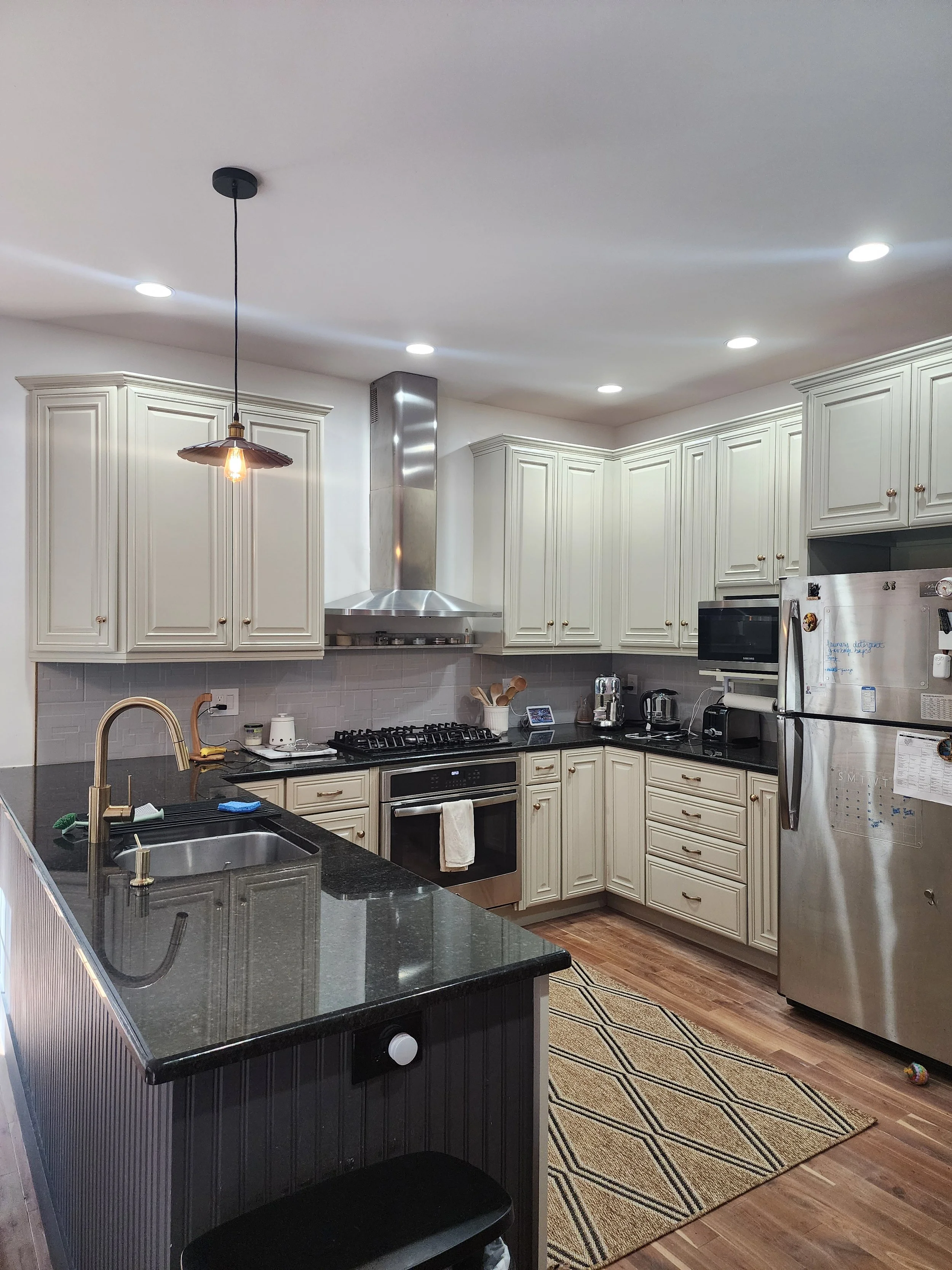 AFTER  —  Painted cabinets, new pendant, fixtures, curated counters, rug