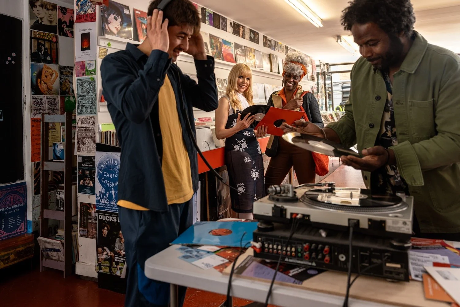Paloma Faith holds a vinyl record among guests at Flashback Records in London, as one guest listens on headphones and another places a record on a turntable.