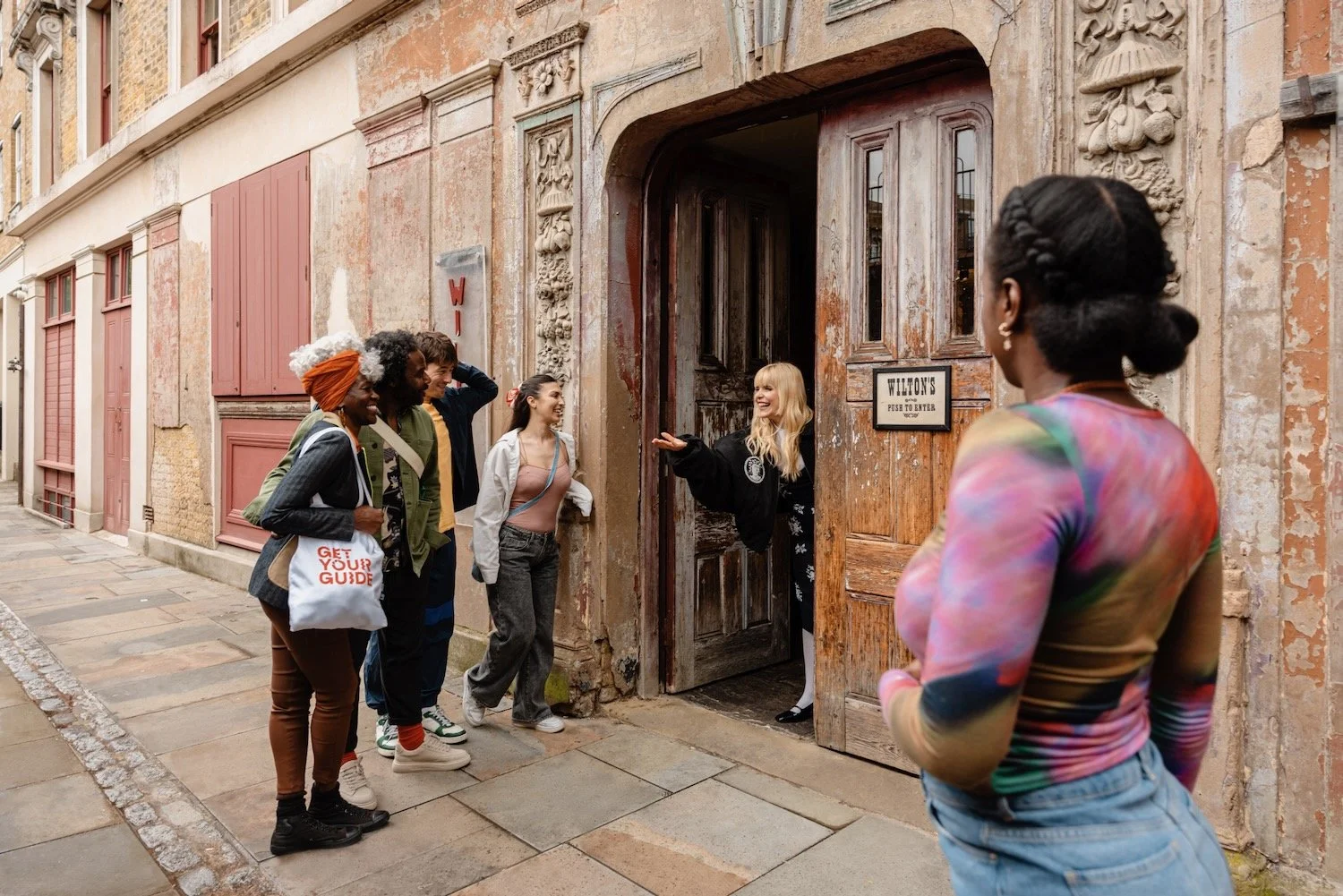 Paloma Faith gestures her guests toward the wooden doors of Wilton's Music Hall on a cobbled East London alley.