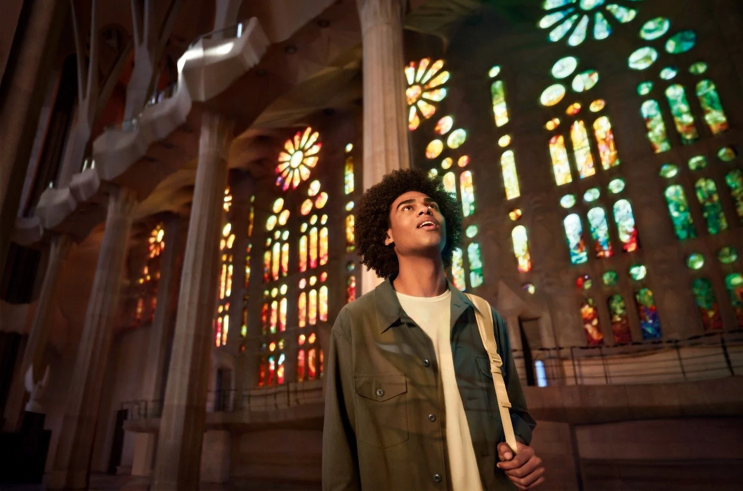 Man looking up, in front of stained-glass light, Sagrada Família, Barcelona. Make Memories campaign.