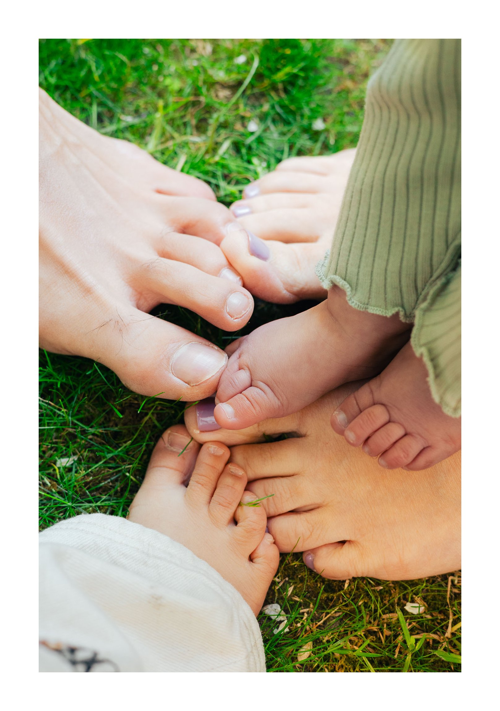 Multiple feet, including two children's, resting on grass.