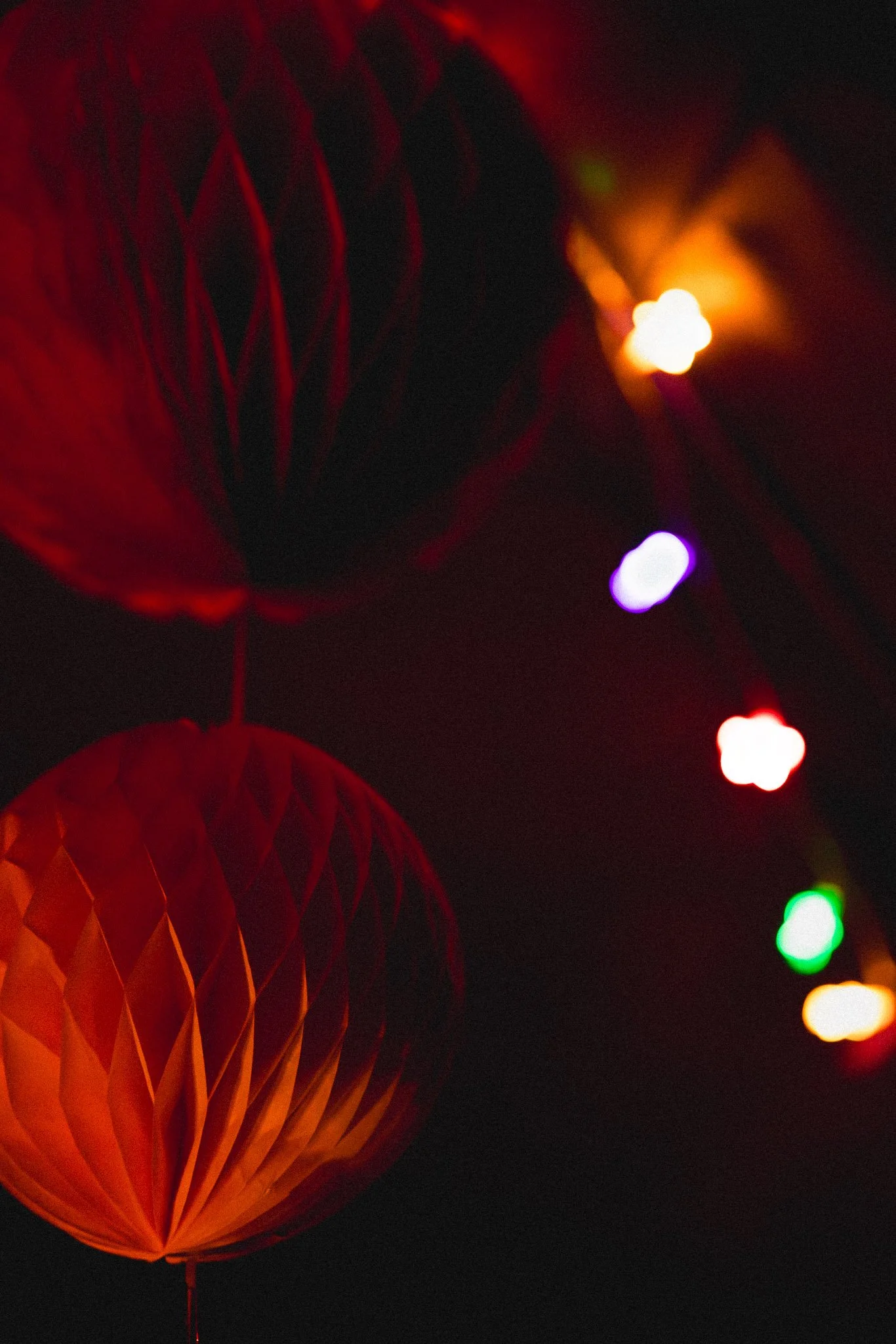 Red paper lanterns and colorful string lights against a dark background.