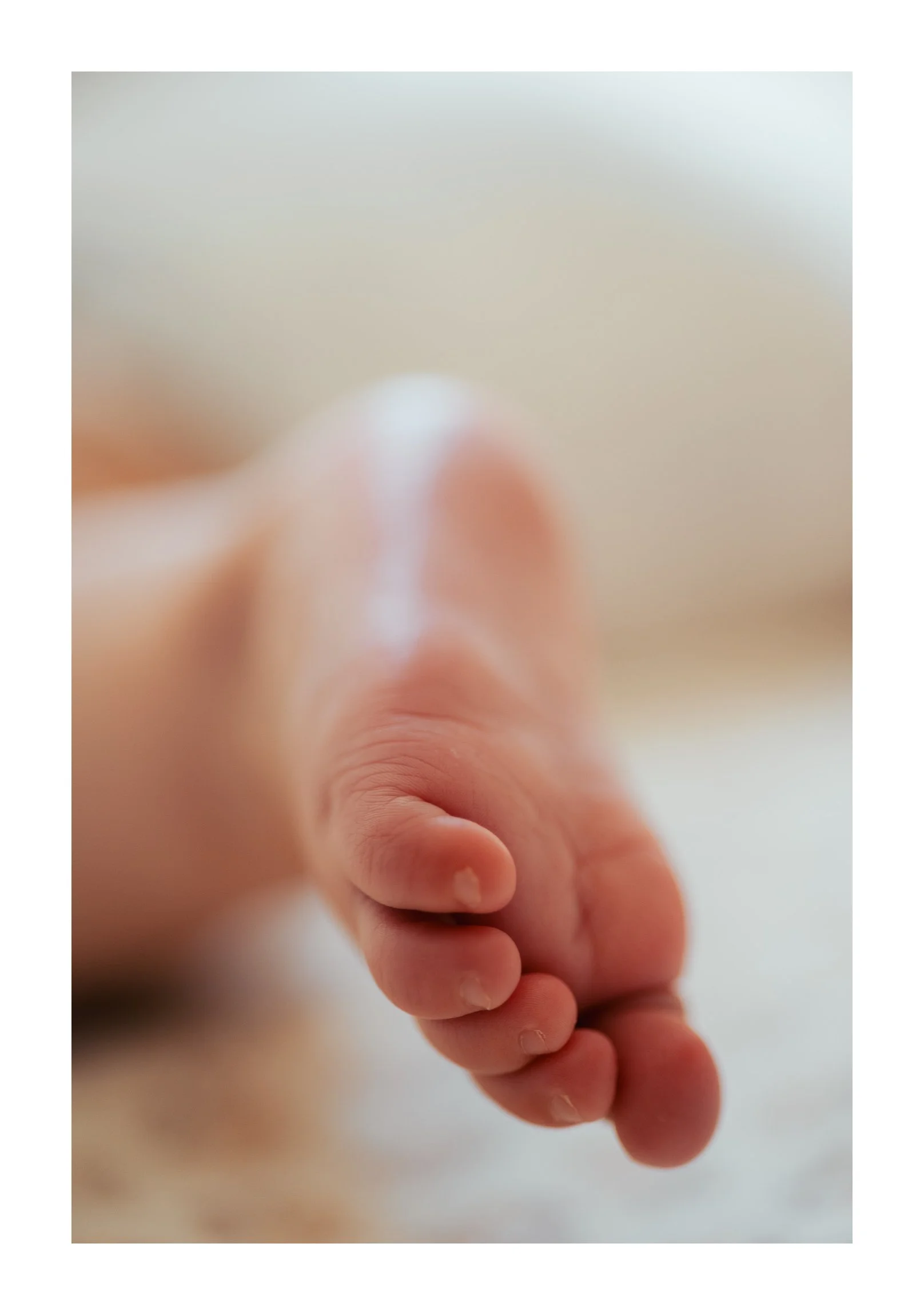 Close-up of a baby’s hand gripping an adult’s finger against a neutral background.