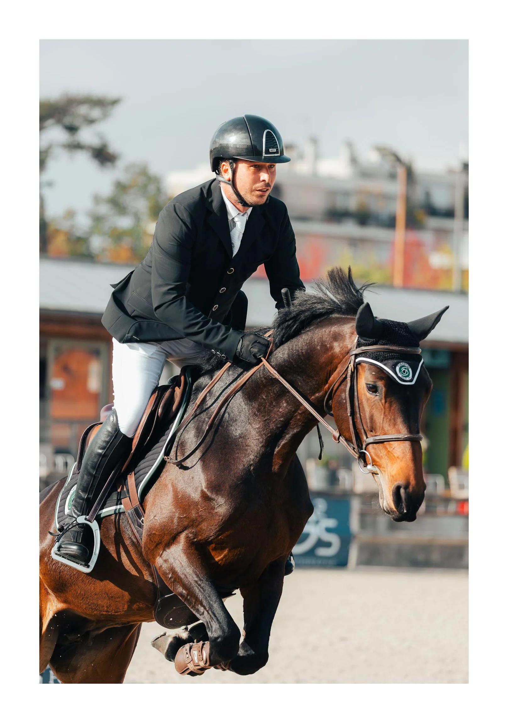 A man in equestrian gear riding a galloping brown horse outdoors.