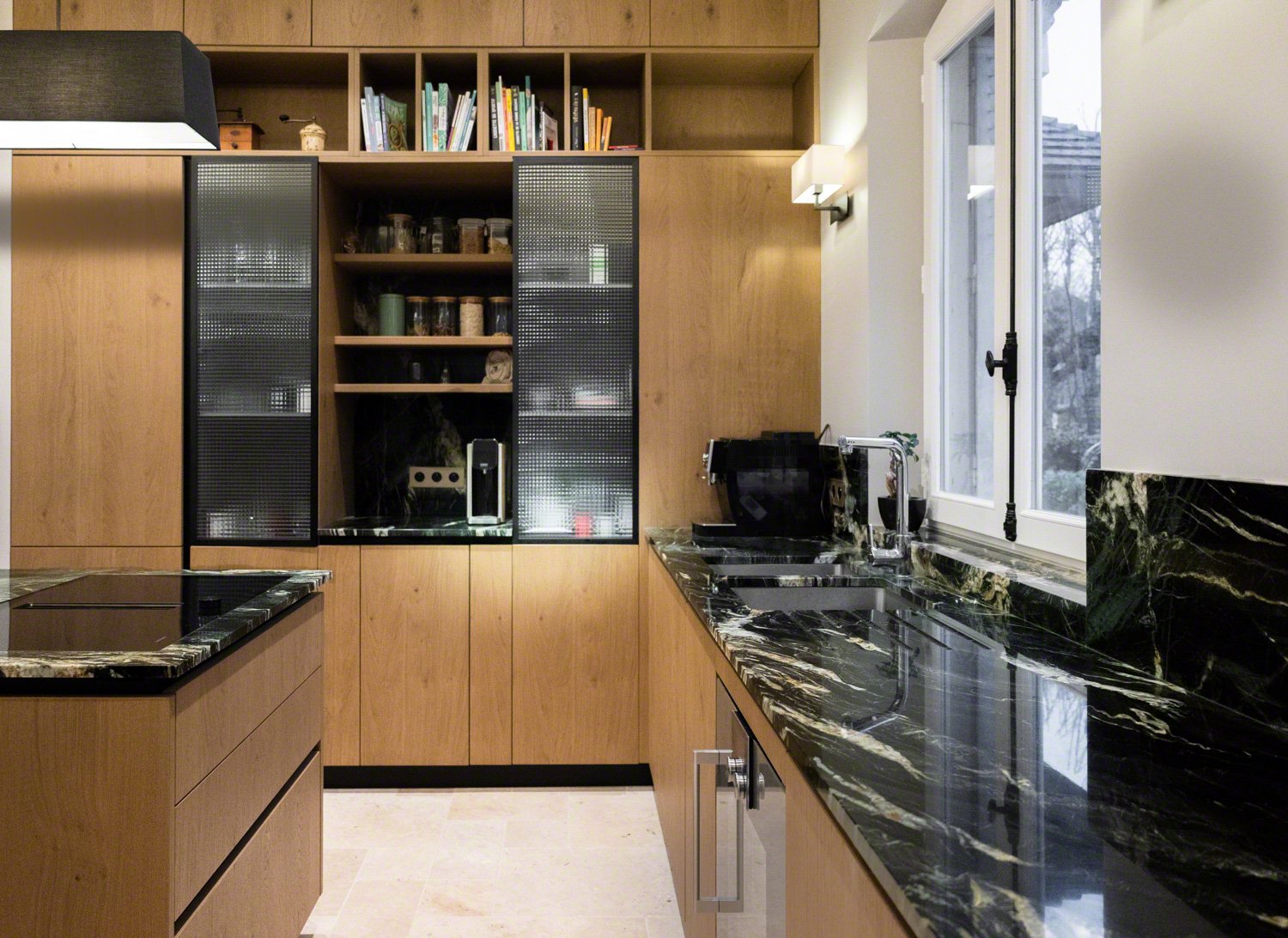Modern kitchen with wood cabinets, black marble countertops, and a large window. Black sink and kitchen appliances are visible.