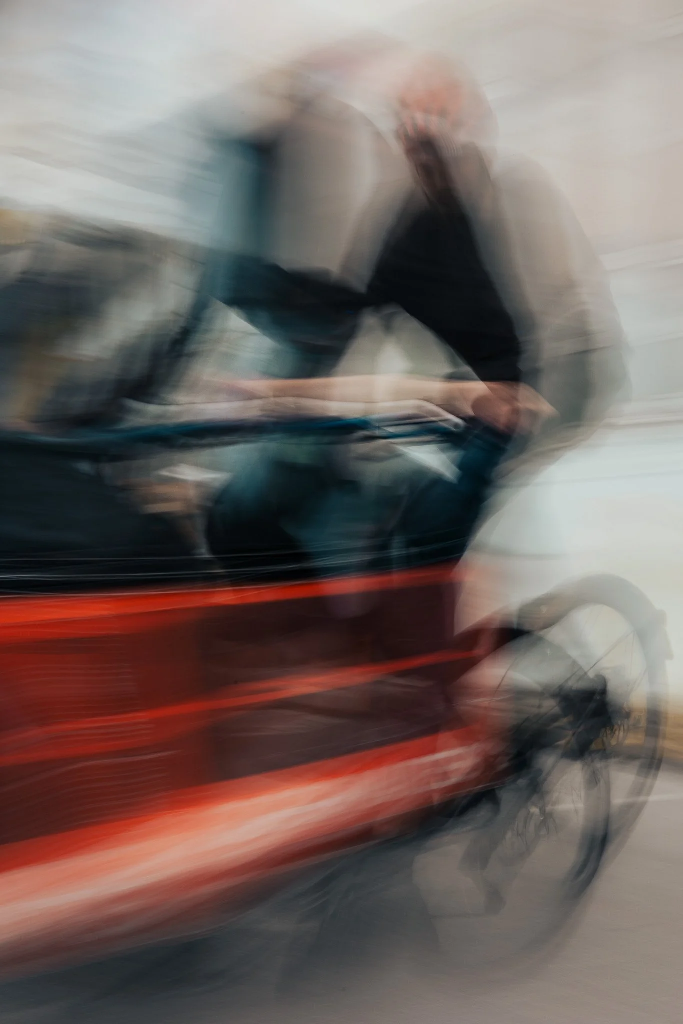 Blurred photo of a person riding a red bicycle, with motion blur suggesting movement.