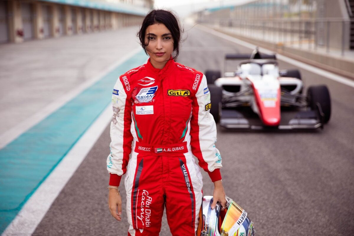 Female race car driver in a professional racing suit, preparing to compete on the track.