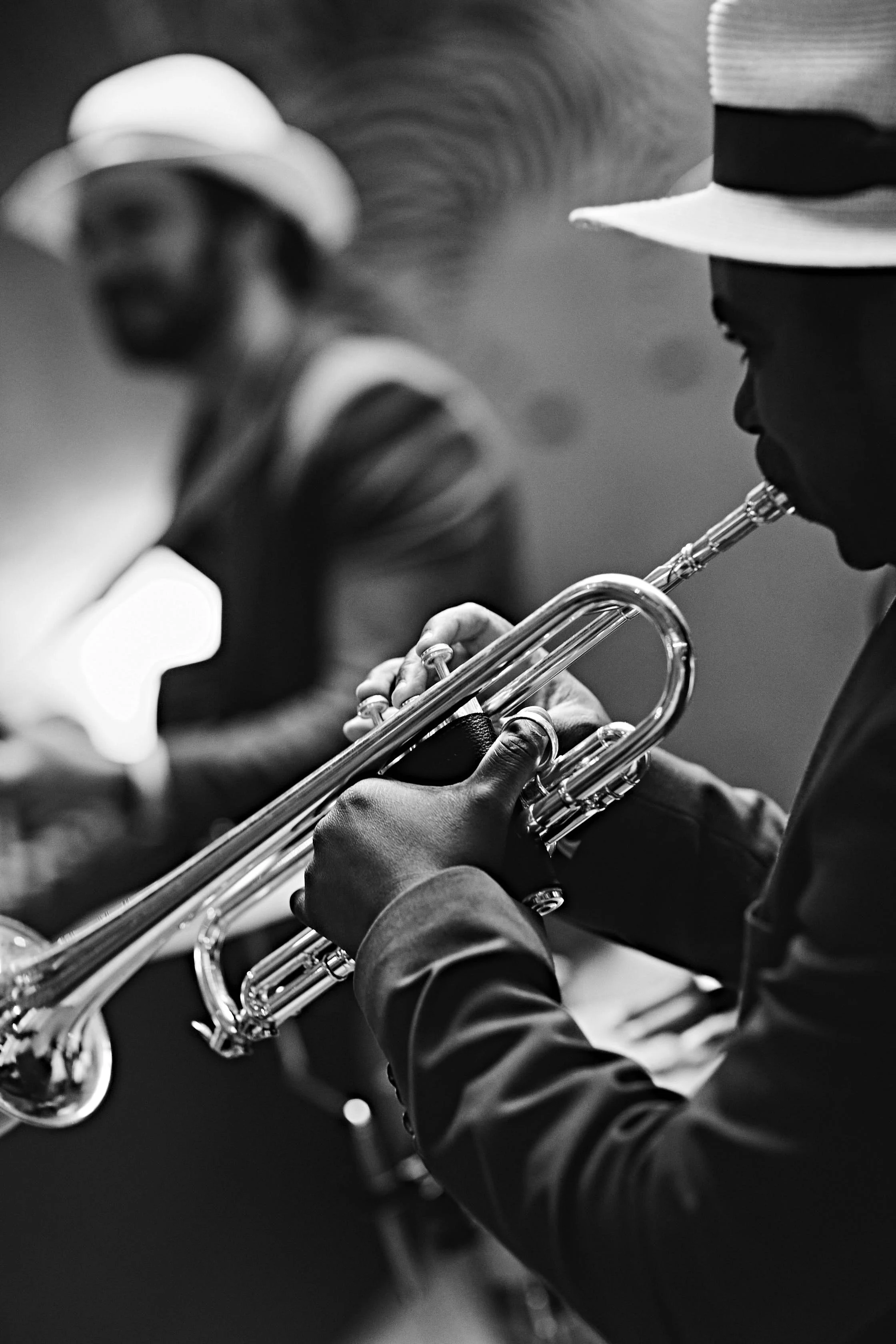 A black and white image of two musicians, one playing the trumpet and the other possibly playing a saxophone, both wearing hats.