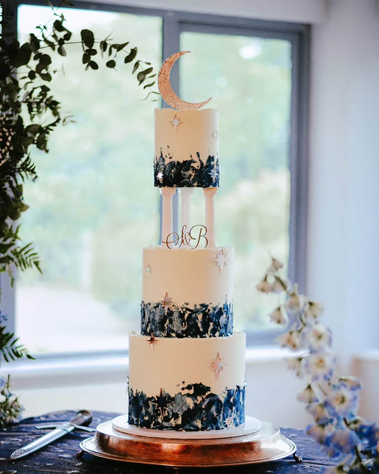 Sarah &amp; Blake had a clear vision for their wedding cake. 

Classical-style pillars, giving it an elevated, regal presence with clean white buttercream providing a crisp contrast to the deep blues and celestial accents. 

The perfect blend of eleg