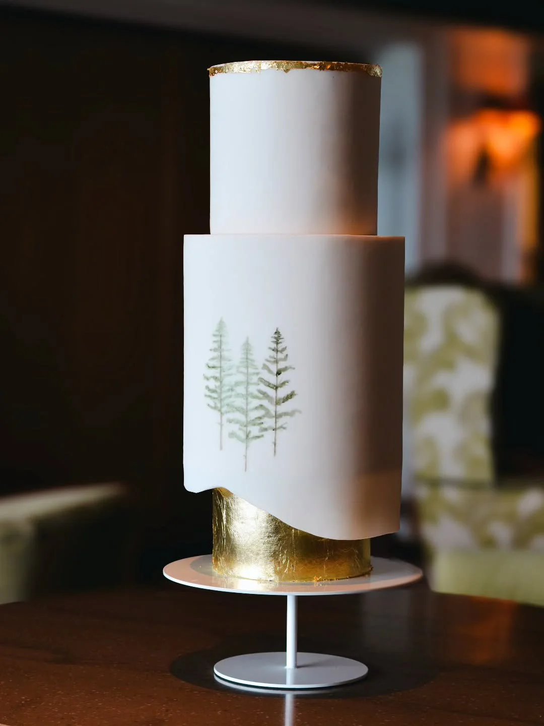 Elaine &amp; David 

Soft, simple, and modern 🤍

This fondant beauty is all about clean lines, handpainted pine trees, and delicate gold details. 
A subtle nature-inspired design, edged with a fondant overhang shaped to give the silhouette of a moun