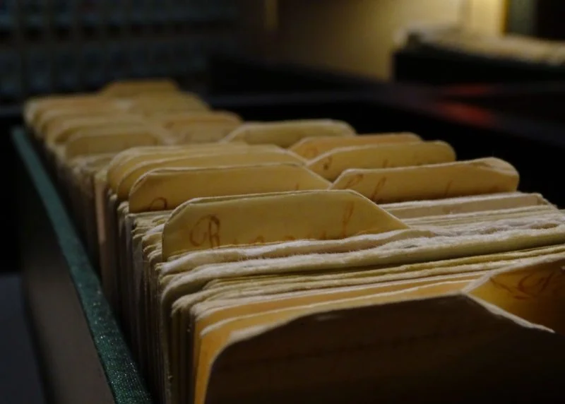 Close-up of vintage archival index cards stored in filing drawers, highlighting the organized records and historical documents used in Quebec genealogy research to trace French Canadian ancestors through church and civil archives.