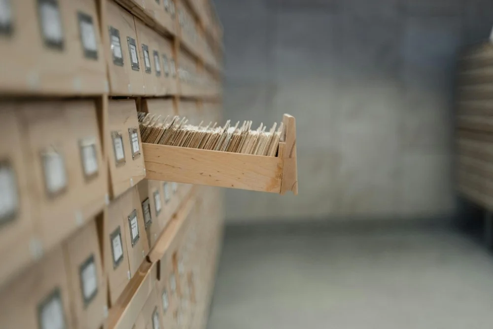 Archive storage room with rows of labeled file drawers; one drawer is pulled open to reveal neatly arranged folders.