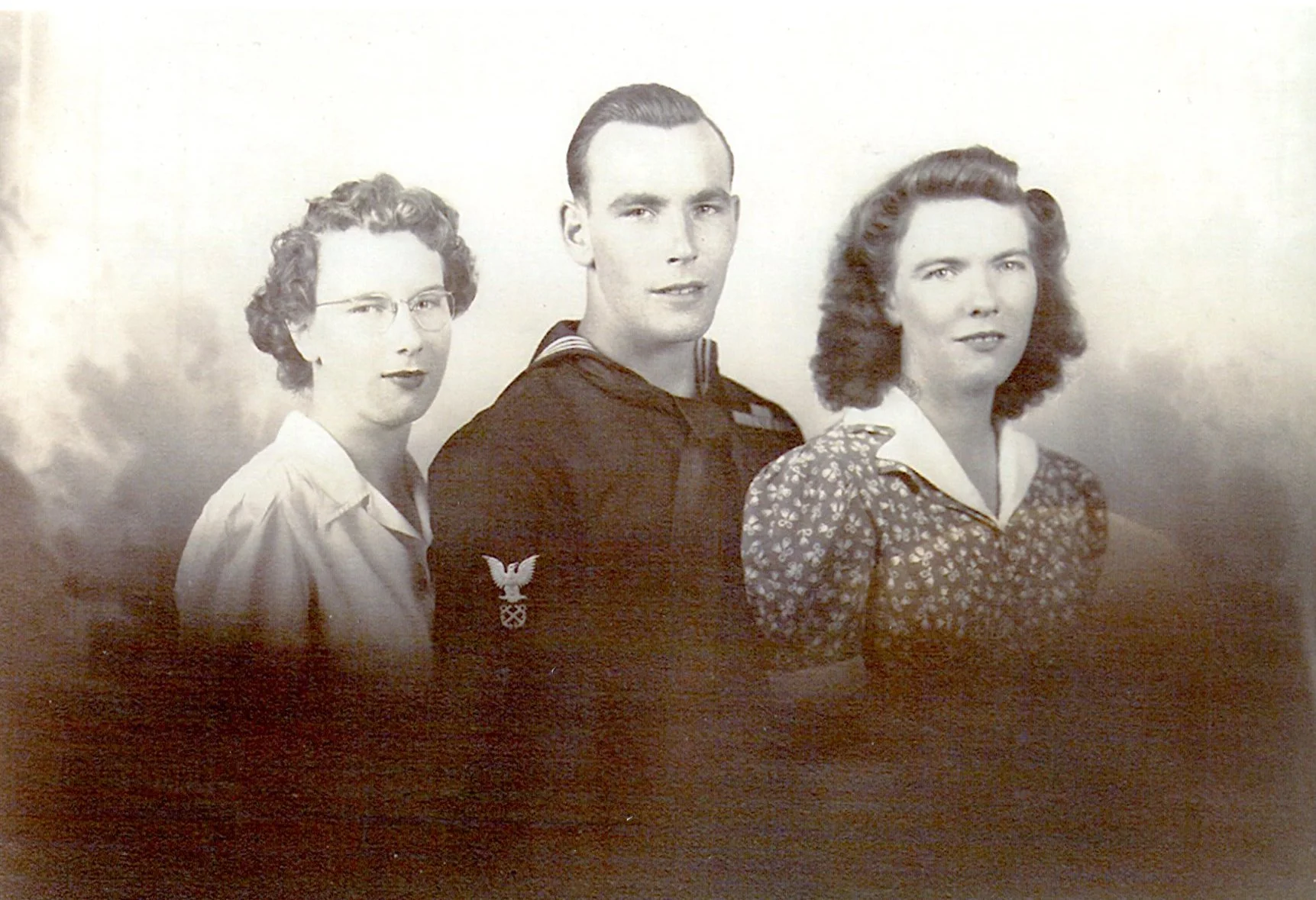 Two women and a man in a studio photo dressed in 1940s era fashion