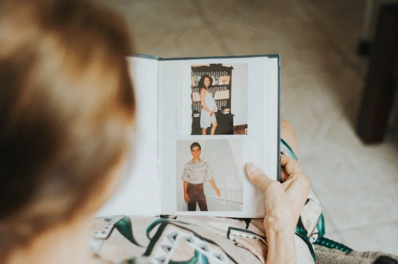 Person looking through a family photo album with old portraits while researching how to find your ancestors and family history.