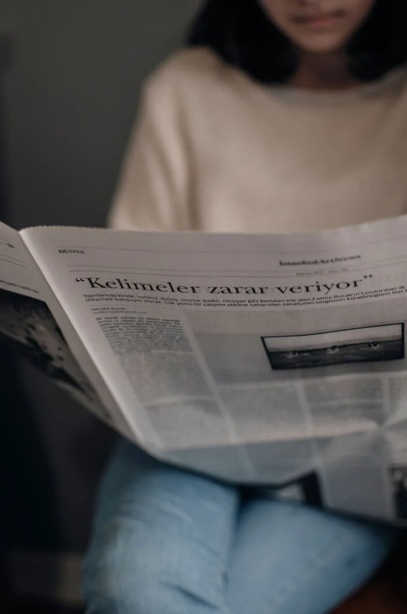 Person reading genealogy newspapers to discover ancestor stories and uncover clues hidden in historical newspaper archives.