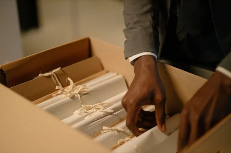 Archival folders filled with documents are carefully organized inside a storage box.