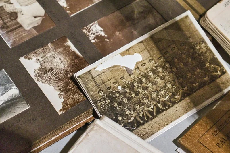Closeup of an old photo album with vintage prints and a sepia group photo on top.