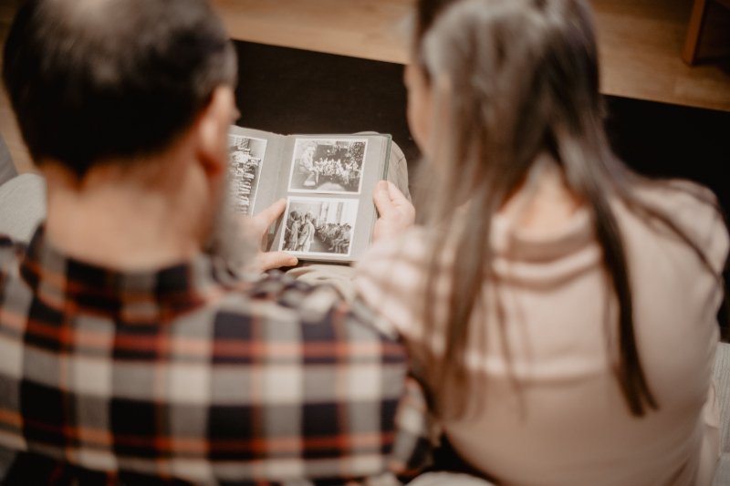Couple looking through an old family photo album together while learning how to find your ancestors and explore their family history.