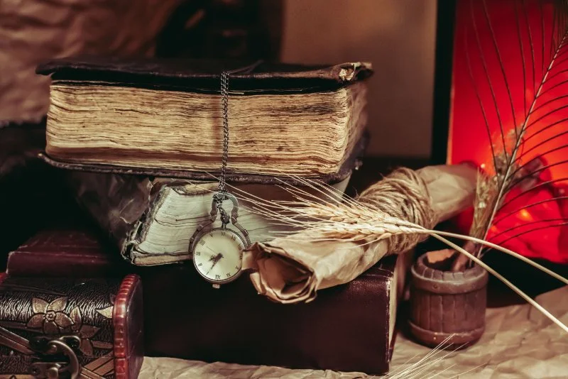 A vintage still life arrangement with old books, a pocket watch, and a rustic setting