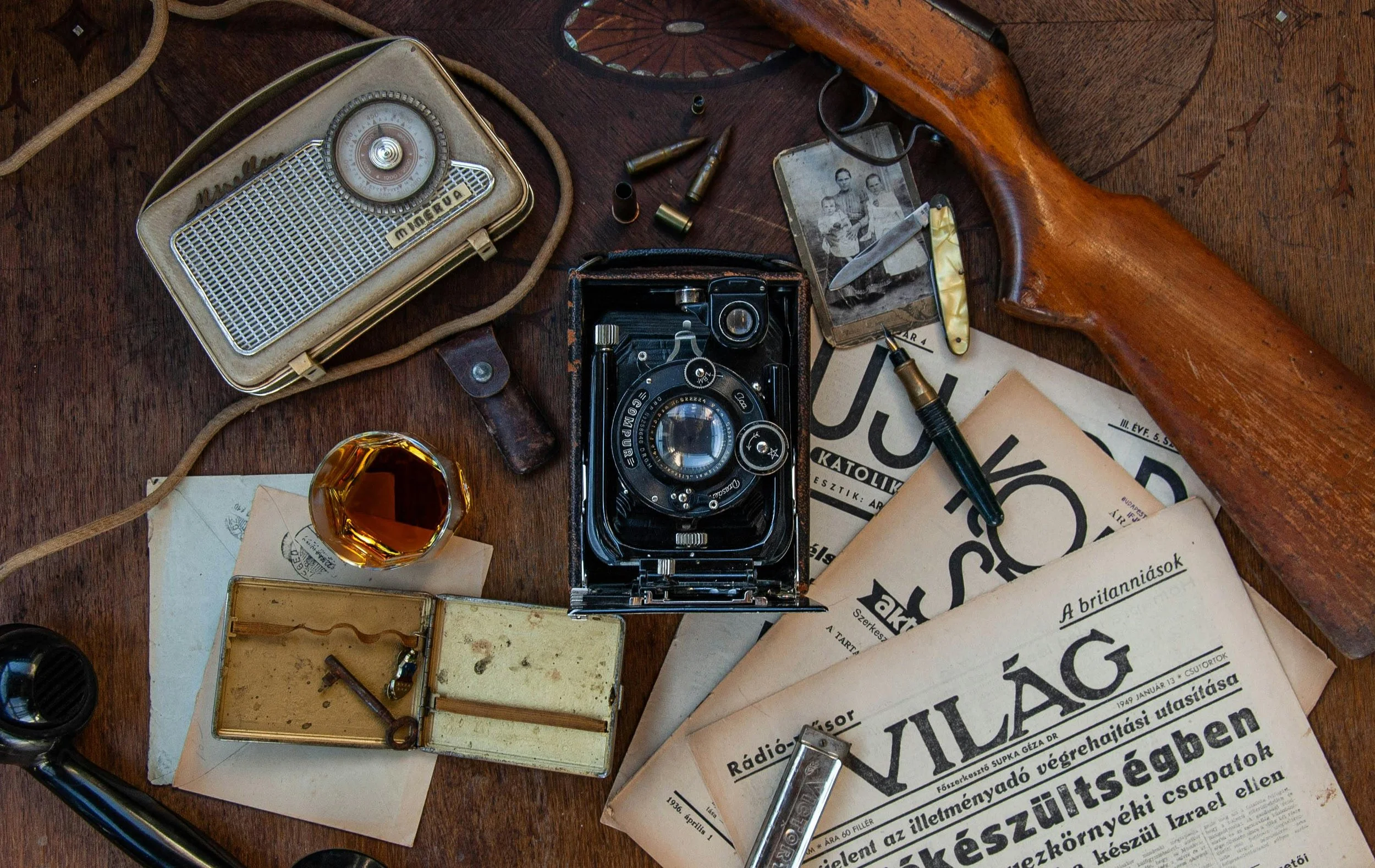 Antique camera, radio, newspapers, and photo on wooden table
