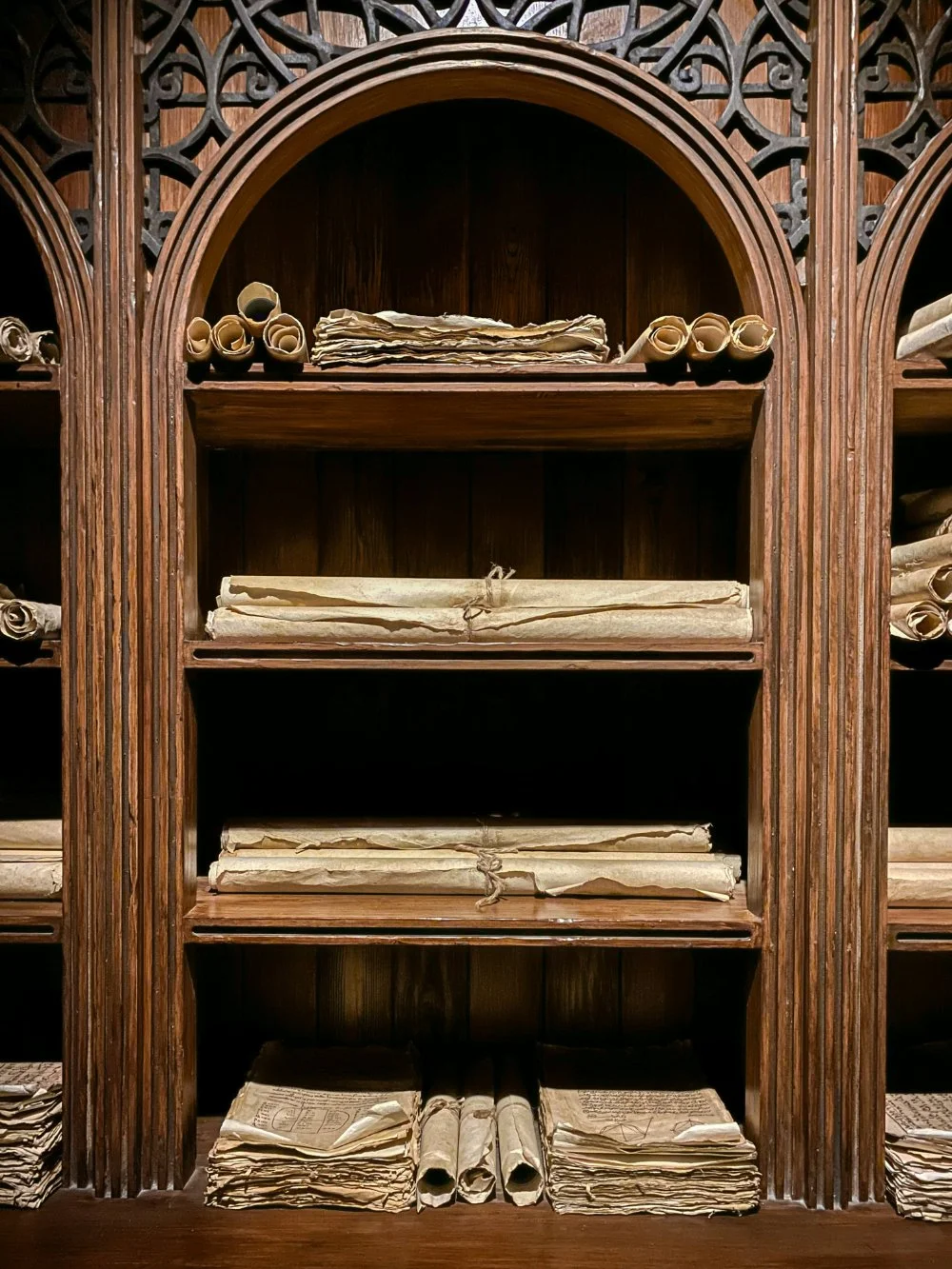 Vintage wooden archive shelves filled with rolled and stacked historical documents, evoking library archives and online collections used for genealogy research.