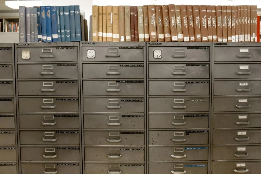 Metal filing cabinets with labeled drawers and index books on top, suggesting archived tax records and long-term record storage.