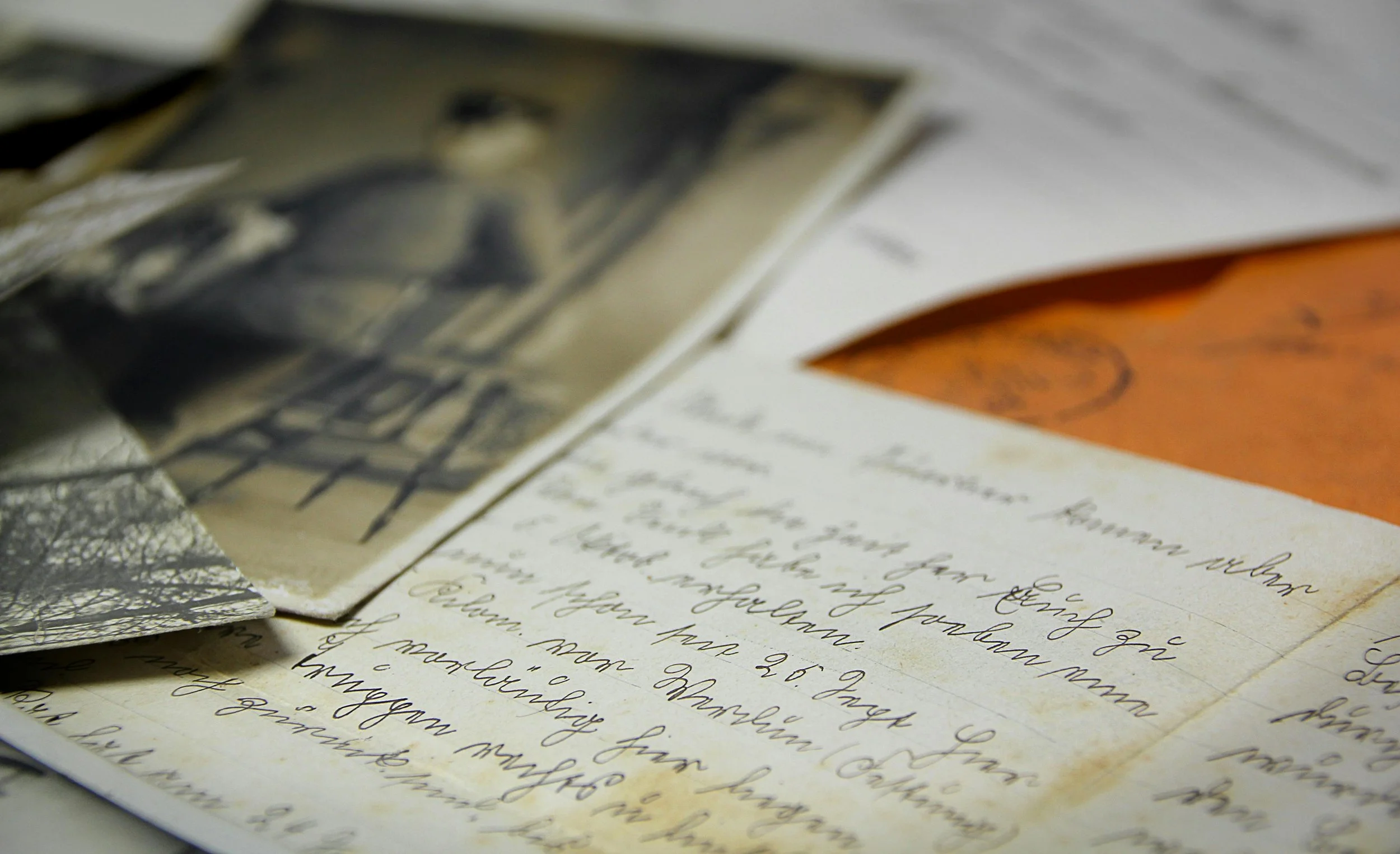 Close up of handwritten old letters and faded vintage photographs, highlighting the details found when you re-examine genealogy records.