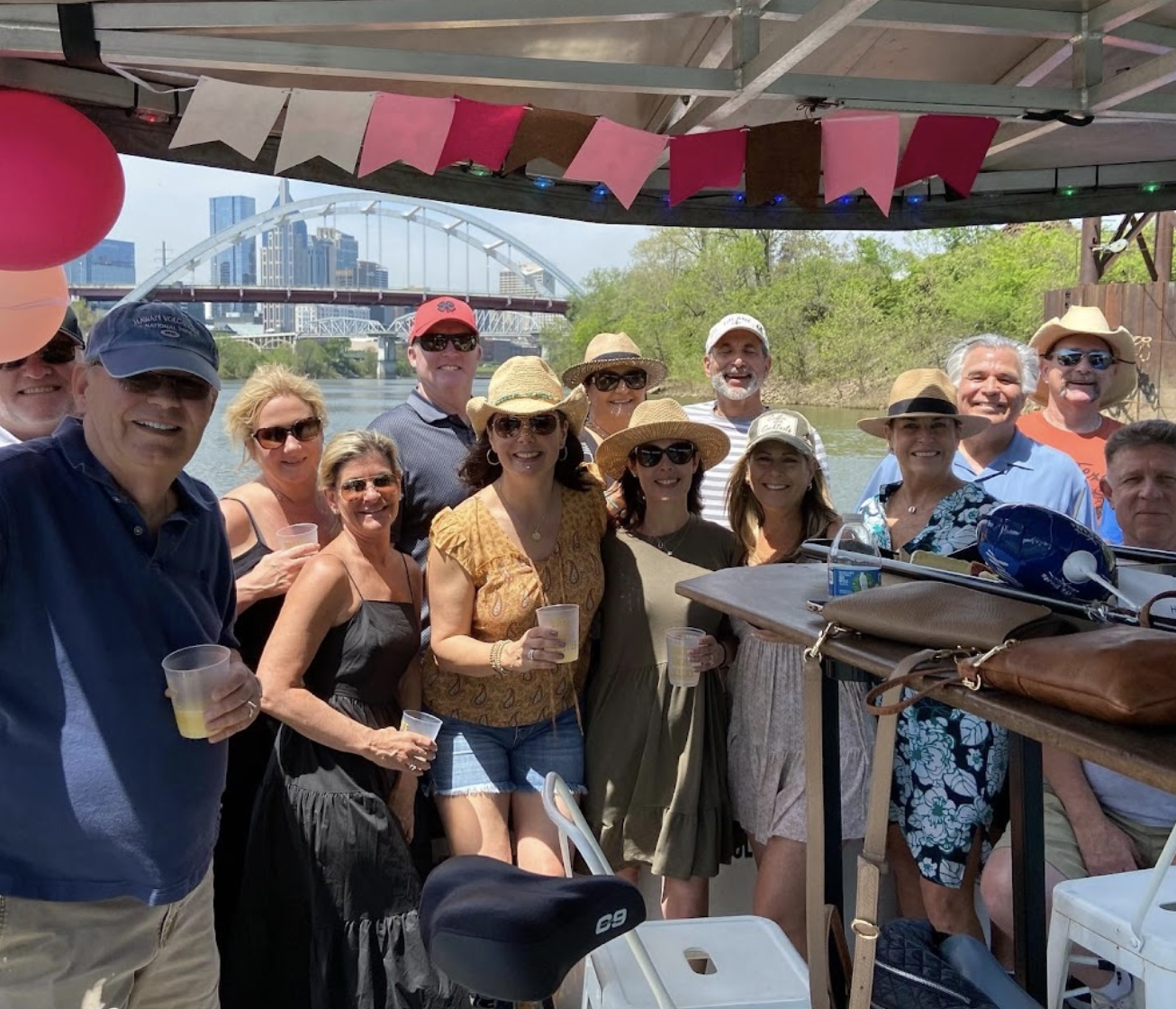 A blend of adults celebrating a birthday party smile and pose on the bow of RQV's Pedal Pontoon