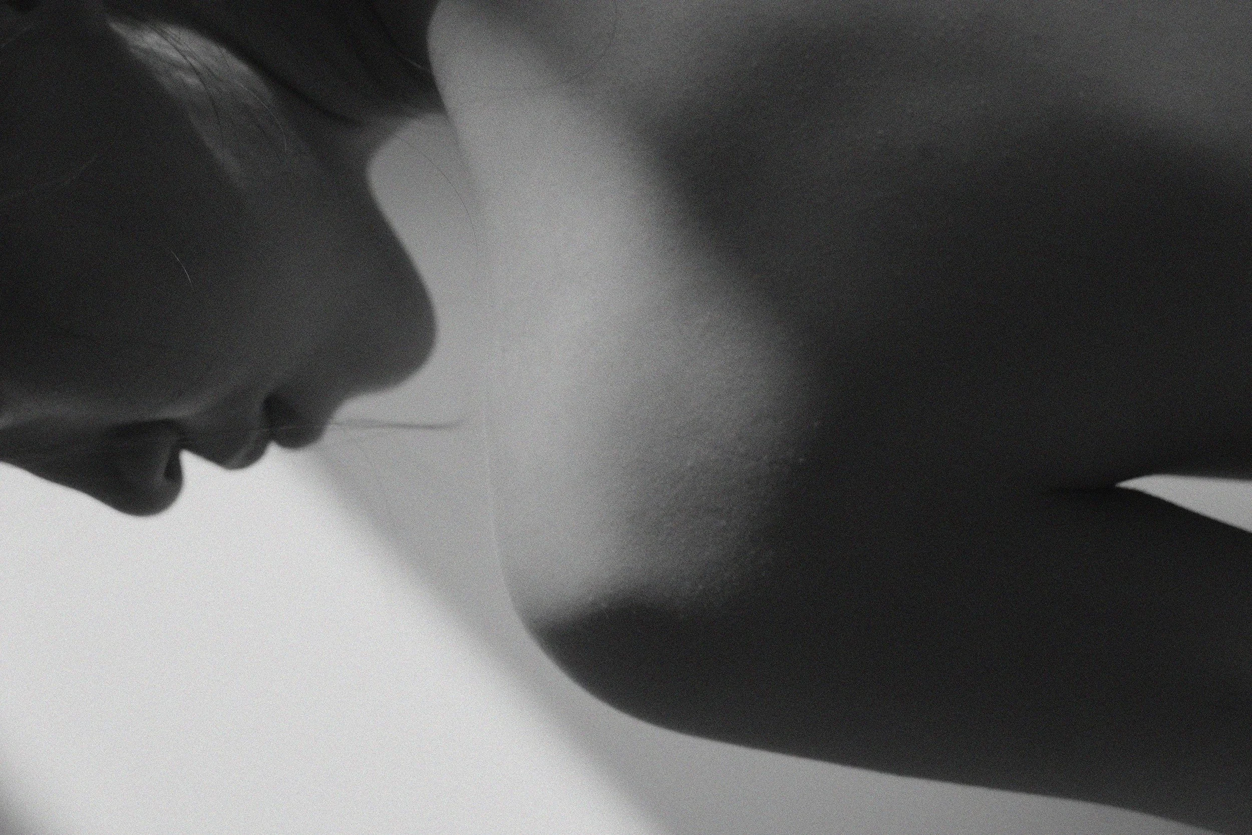 Close-up of a person's profile with dark skin and black hair, displayed in grayscale.