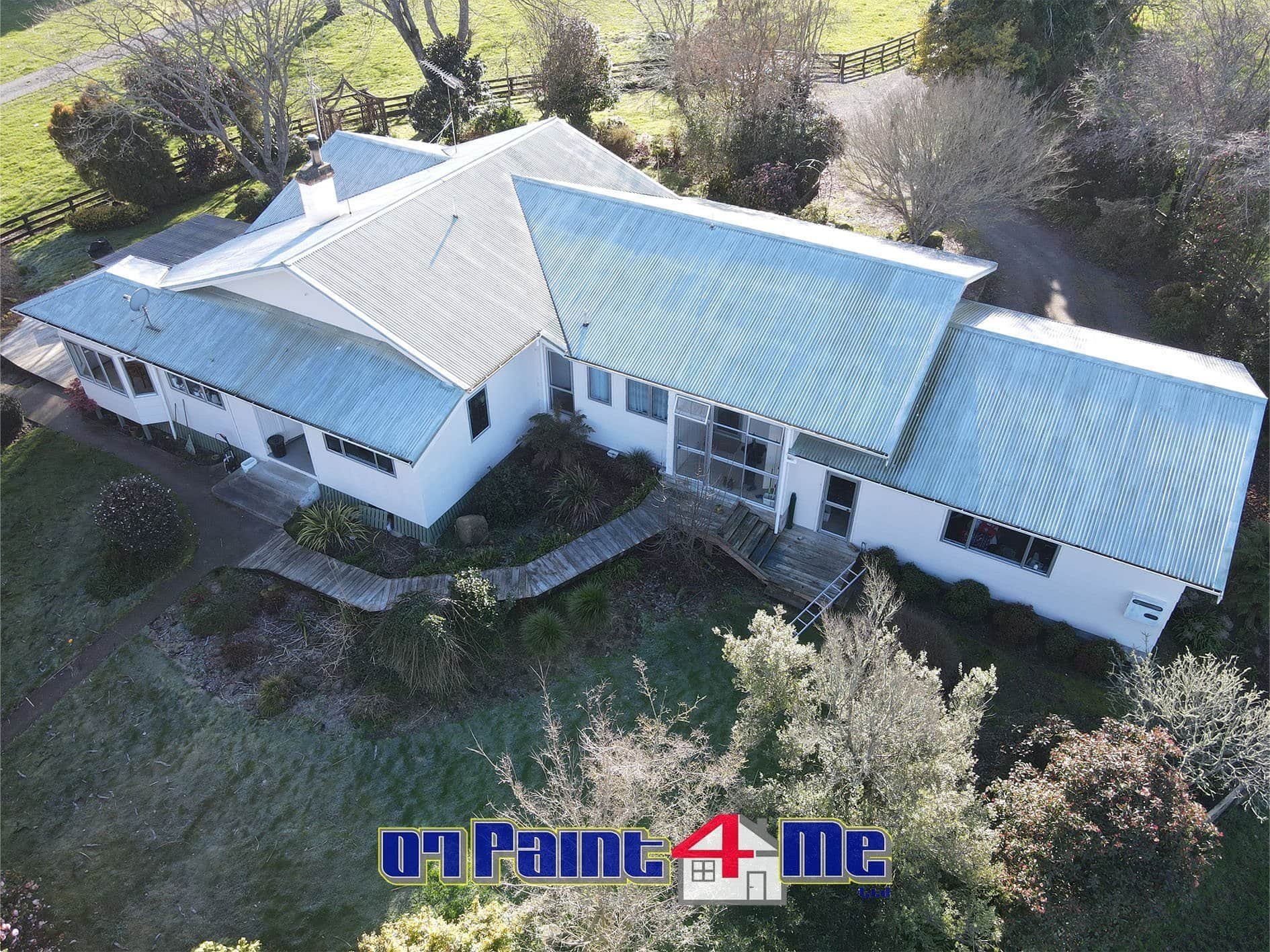 Aerial view of a farmhouse with a very neglected painted roof before the new paint job. There is a "07Paint4Me Ltd" logo at the bottom of the image.