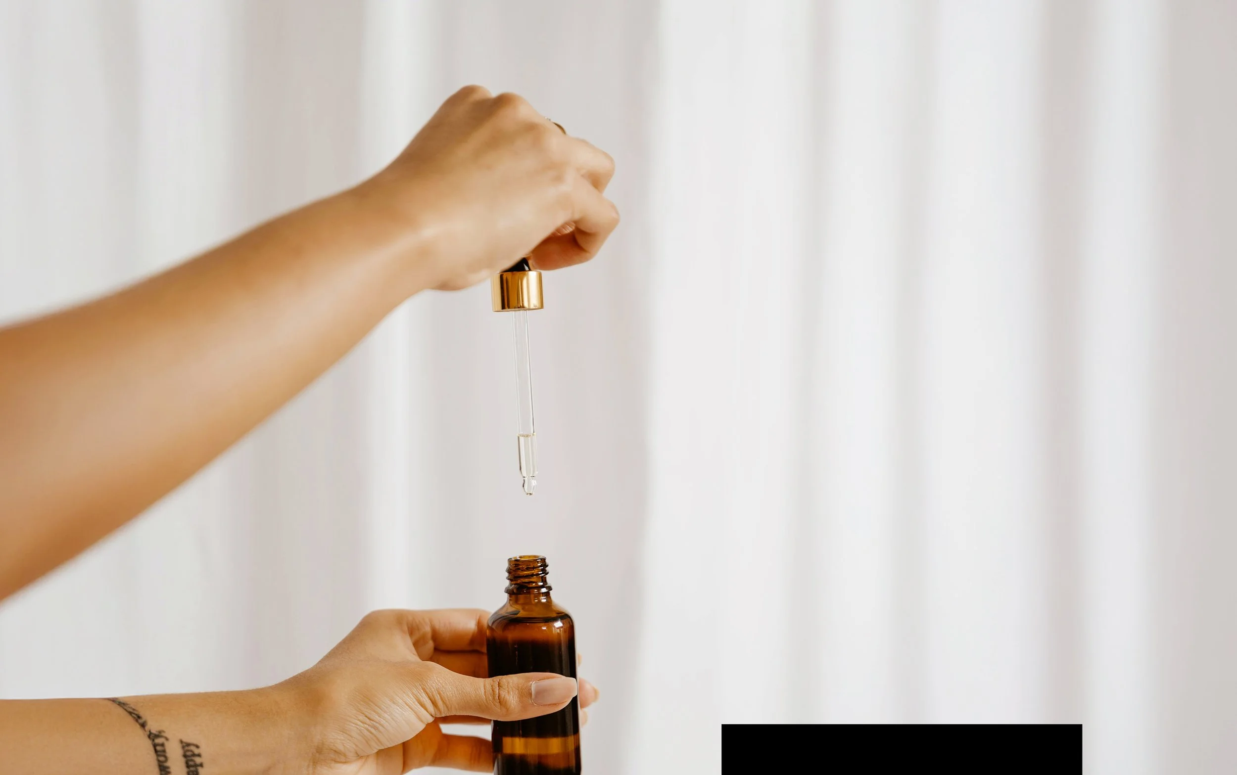 Hands opening an essential oil bottle, with dropper held above bottle