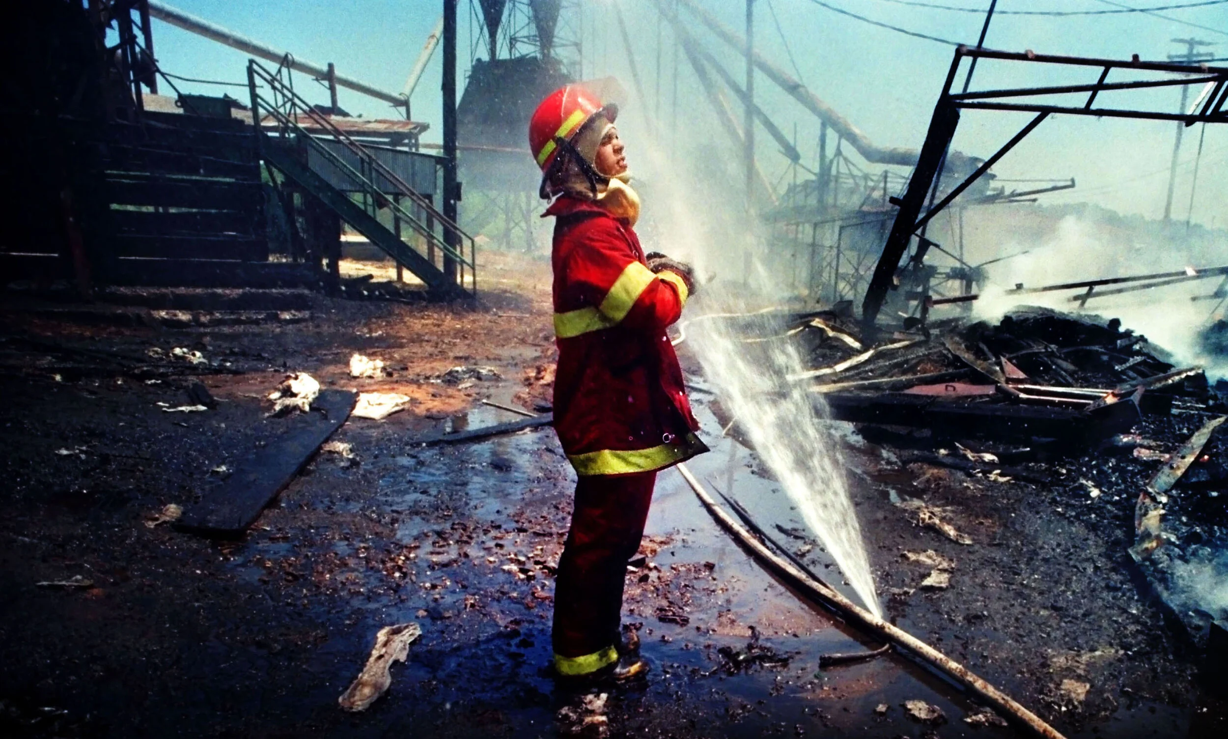  Firefighter Charles Shore cools off in the spray from a damaged hose while looking for hot spots in the remains of a charred grain elevator in Sturgis, Miss. 