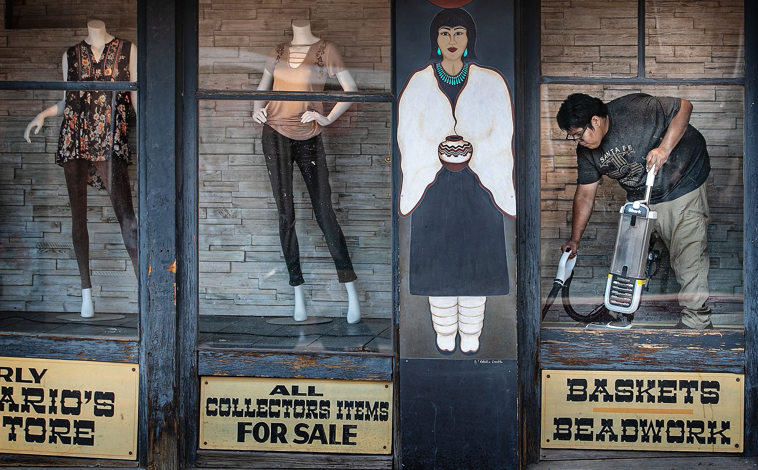  As tourists pass by on a mild summer day, Ryland Bailon (right) tidies up a display window on San Francisco Street at the Original Trading Post on June 22, 2021.   