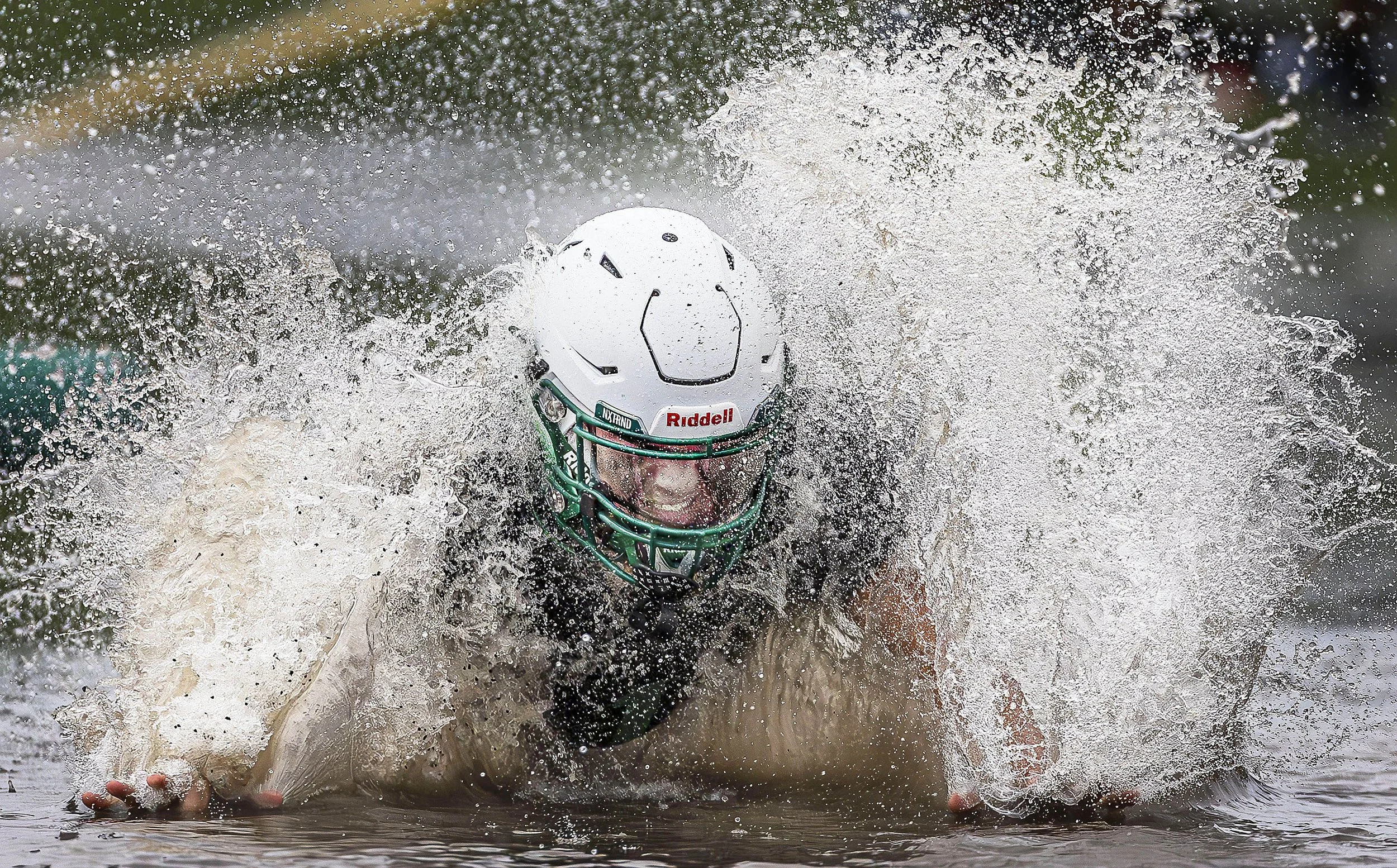  Quarterback Joshua Gonzales takes a slide on the puddled turf as the team retreats indoors during football practice for the Elks at Pojoaque Valley High School on Thursday Sept, 8, 2024. The Elks have been battling Mother Nature to be ready for thei