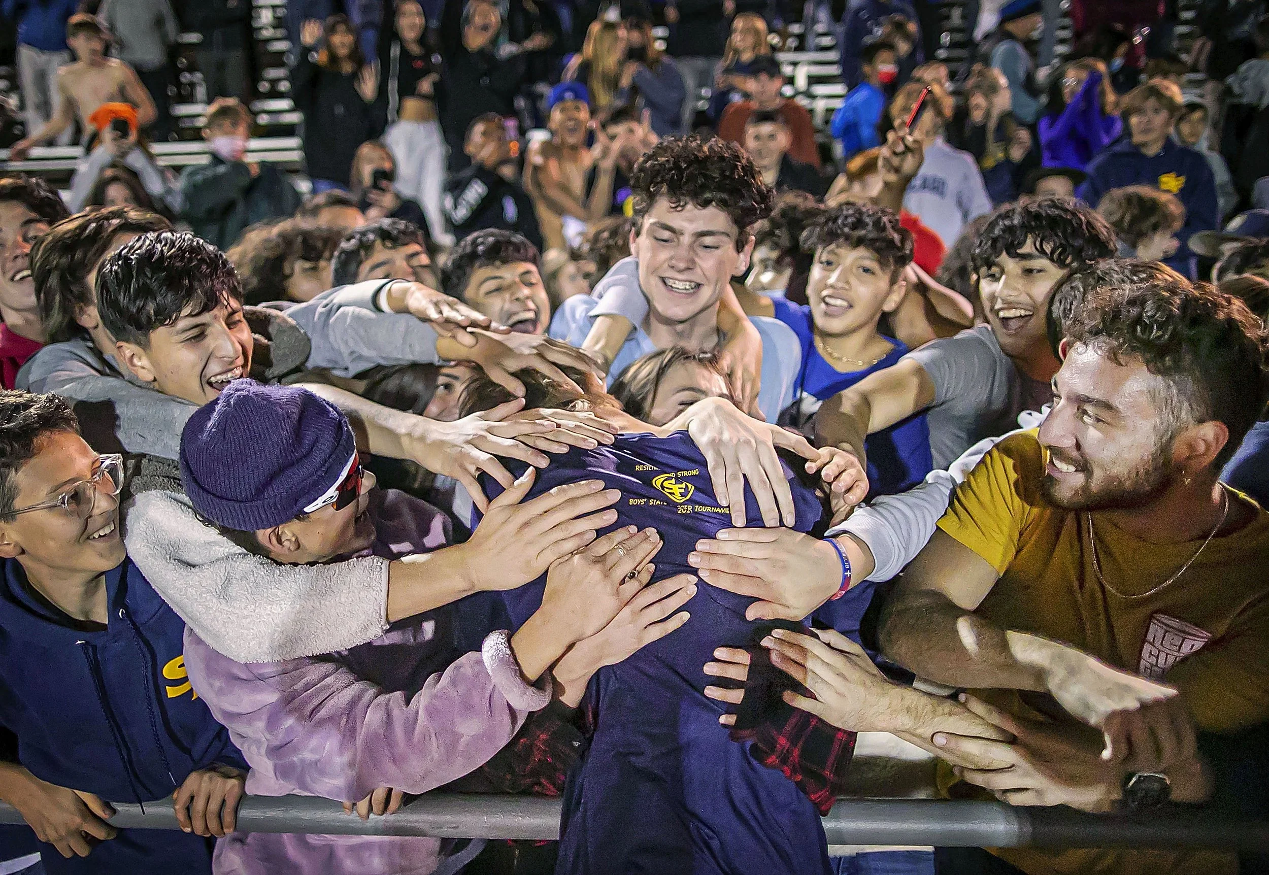  The Demons striker Alex Waggoner is embraced by a crowd of Santa Fe soccer fans after Santa Fe High School’s 4-3 5A State Championship win over Sandia High School at the UNM soccer complex on Nov 5, 2021. This is the school’s first ever State Champi