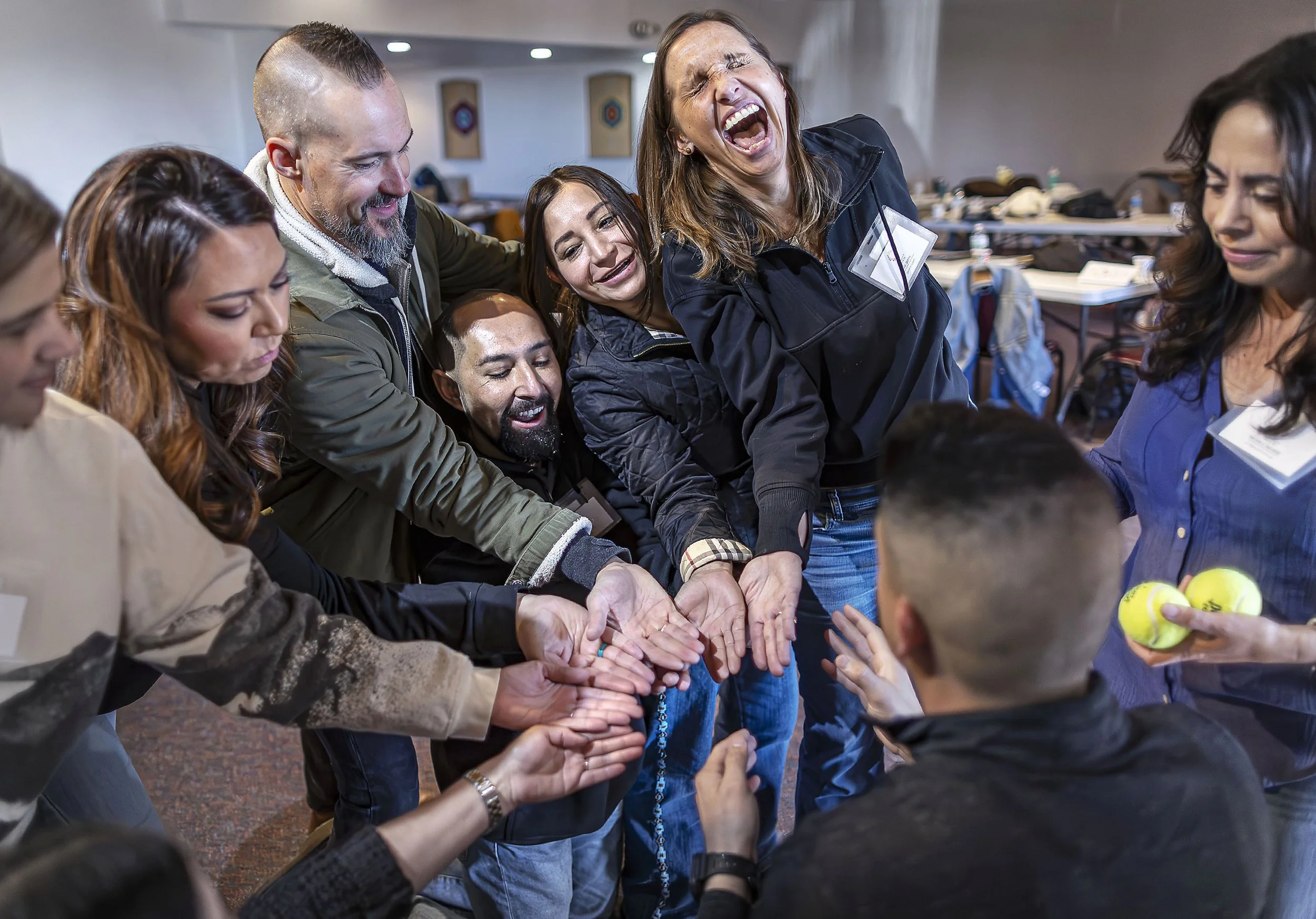  Sara Smith, second from right, cracks up while Michelle George, right, slowly releases tennis balls down their group's hand-slide during a small group teamwork exercise during a Leadership Santa Fe training day at the Santa Fe Women's Club on Saturd