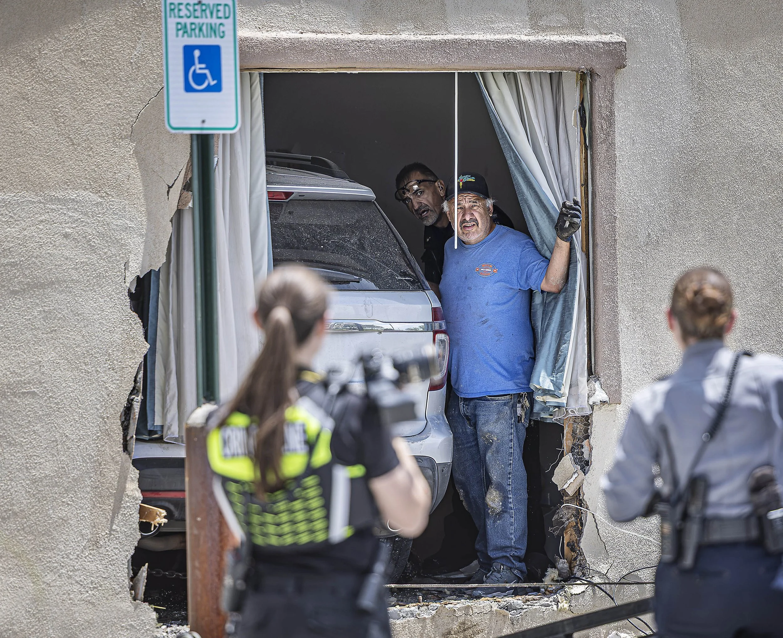  Tow truck driver Chris Padilla, center, and Senior Officer Arthur Maes work at extricating an SUV from the Econo Lodge Inn after it rammed through a hotel wall on Wednesday, July 15, 2026. Santa Fe Fire Department paramedics took the driver, an adul